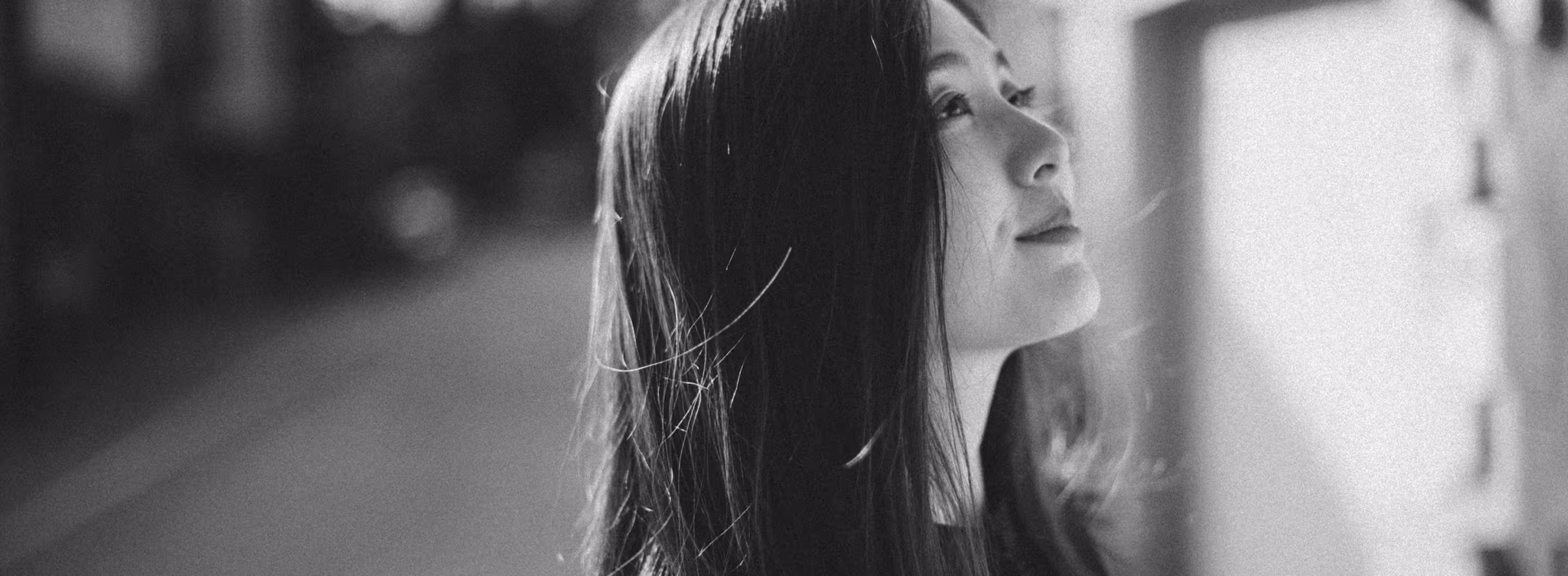 Black and white photo of a woman with long hair looking upward, side profile visible.