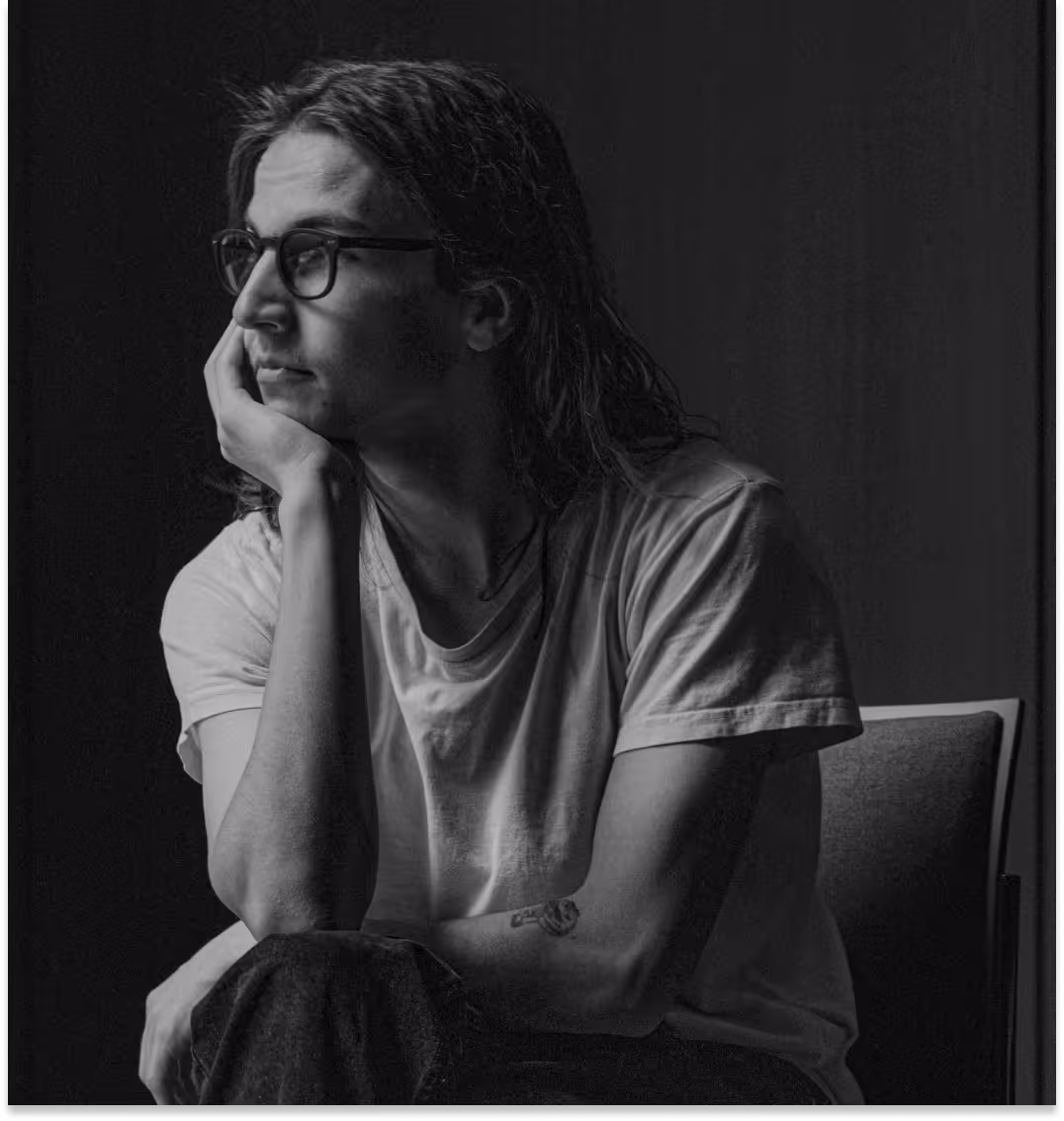 Black and white photo of a man with glasses lost in thought resting head on hand.